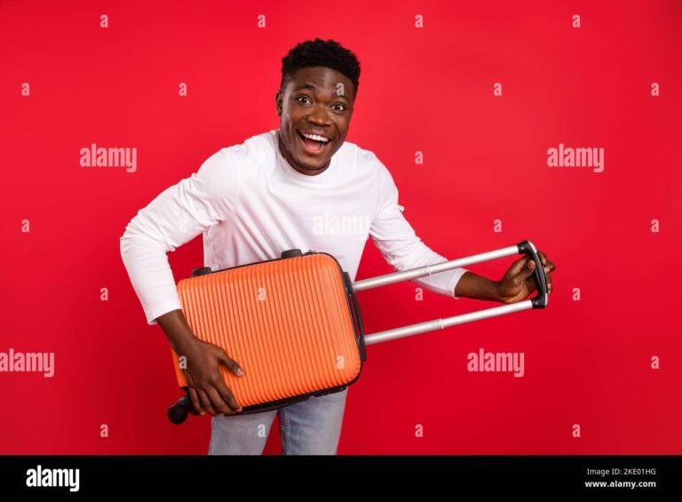 joven sonriente en aeropuerto con maleta roja