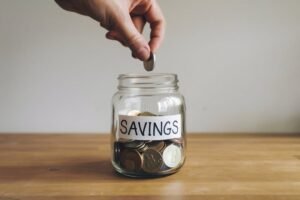 mano colocando monedas en frascos ahorros