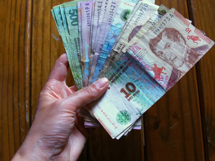 mano sosteniendo billetes argentinos y recibo