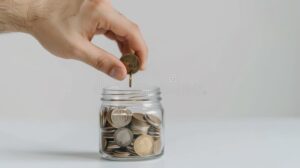 manos colocando monedas en frasco ahorro