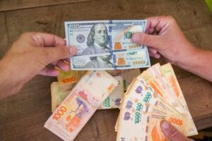 manos intercambiando billetes dolar y peso