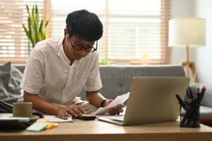 persona calculando gastos con billetes y computadora