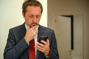 persona preocupada con celular y computadora abierta